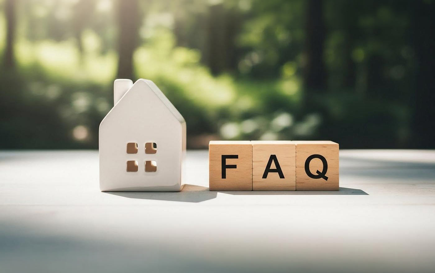 Modellhaus neben Holzklötzen mit der Aufschrift "FAQ"